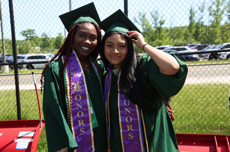 two Honors program students wearing cap and gown at commencement