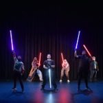 students on stage with lightsabers