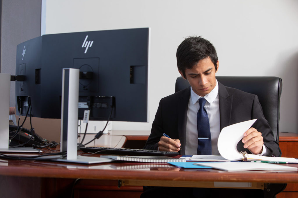 man sitting at a desk looking at notebook