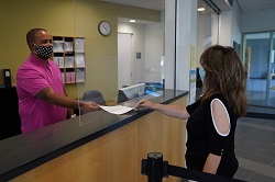staff handing a student a piece of paper at registration desk
