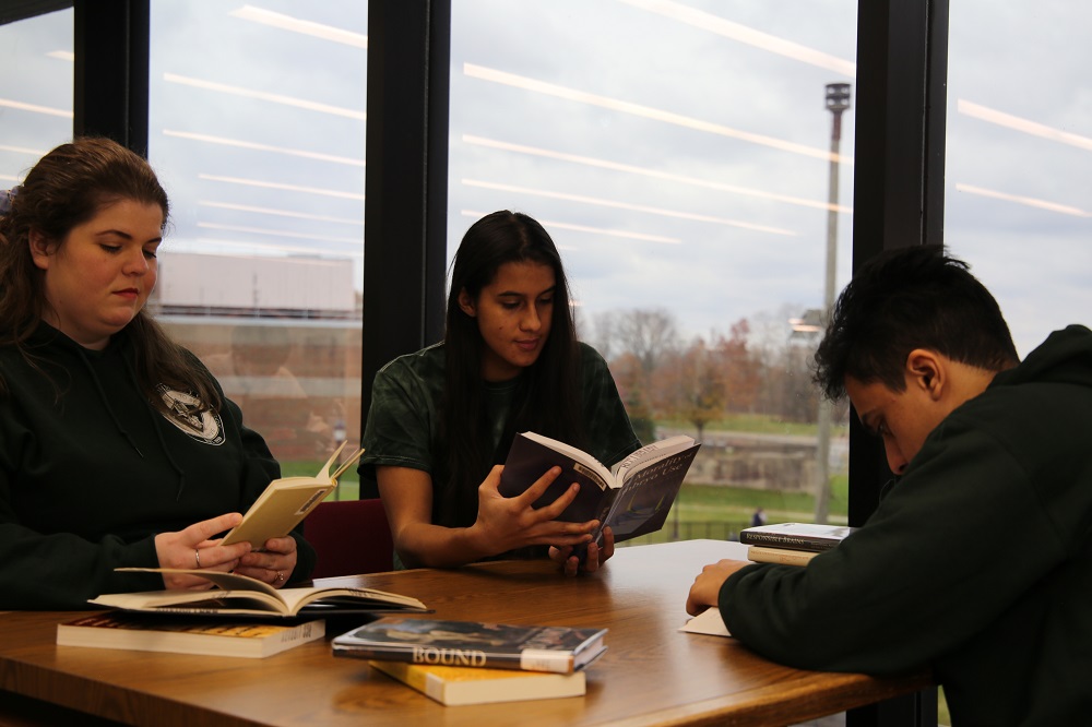three students at a table reading books