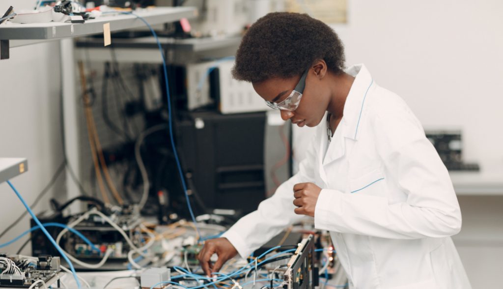 student in lab coat and goggles working with wires