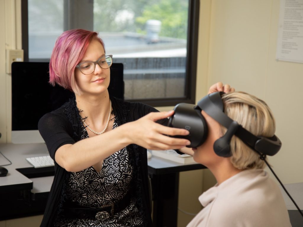 student placing VR goggles on another student