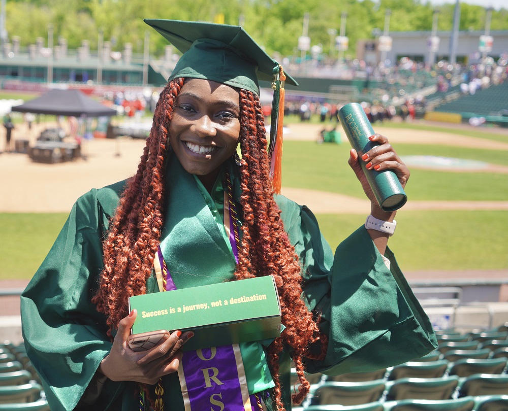 student holding diploma at commencement