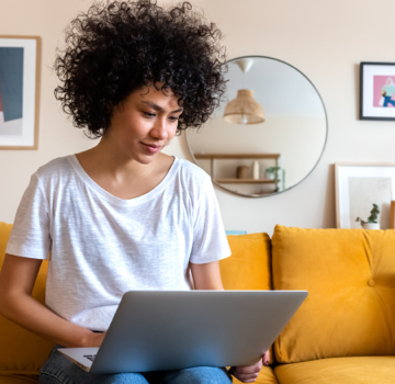 woman sitting on couch looking at laptop