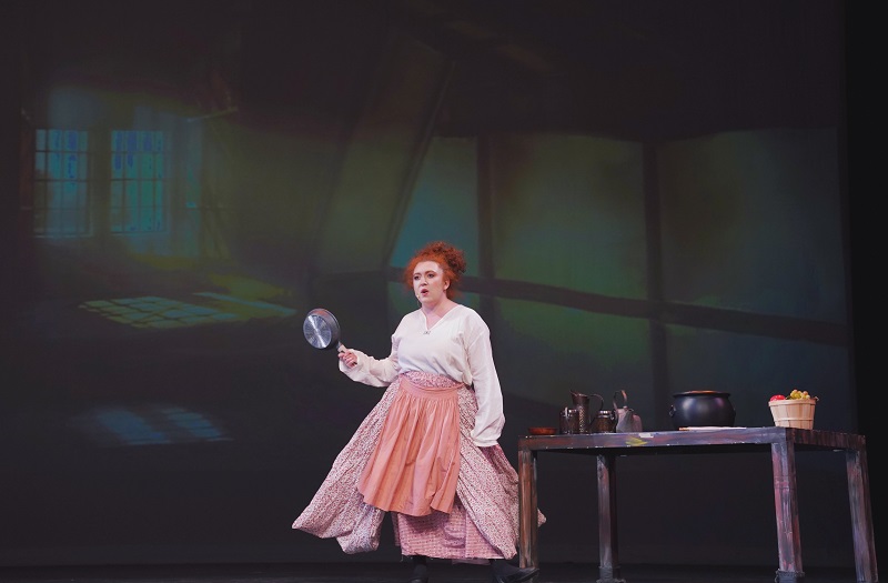 actor on stage holding a frying pan