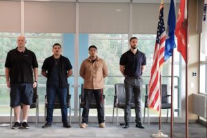 four veterans standing next to flags